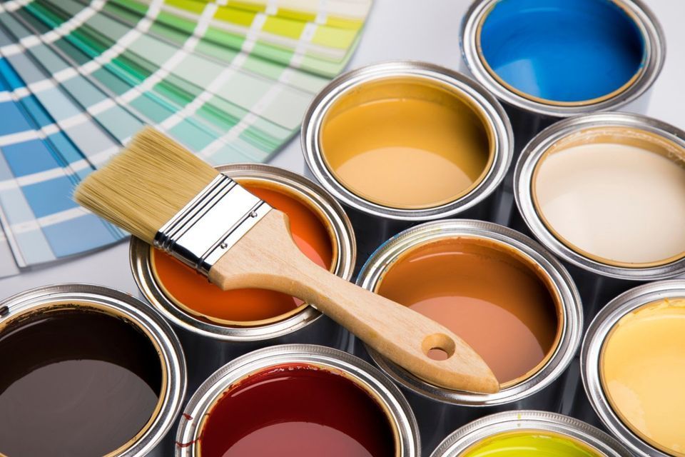 Paint brushes resting on open cans of various colorful paints.