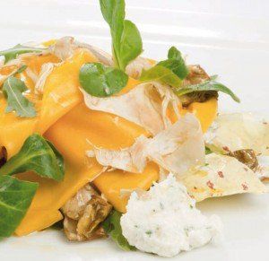 Piatto di pasta al formaggio con basilico fresco e scaglie di parmigiano, servito su un piatto bianco.
