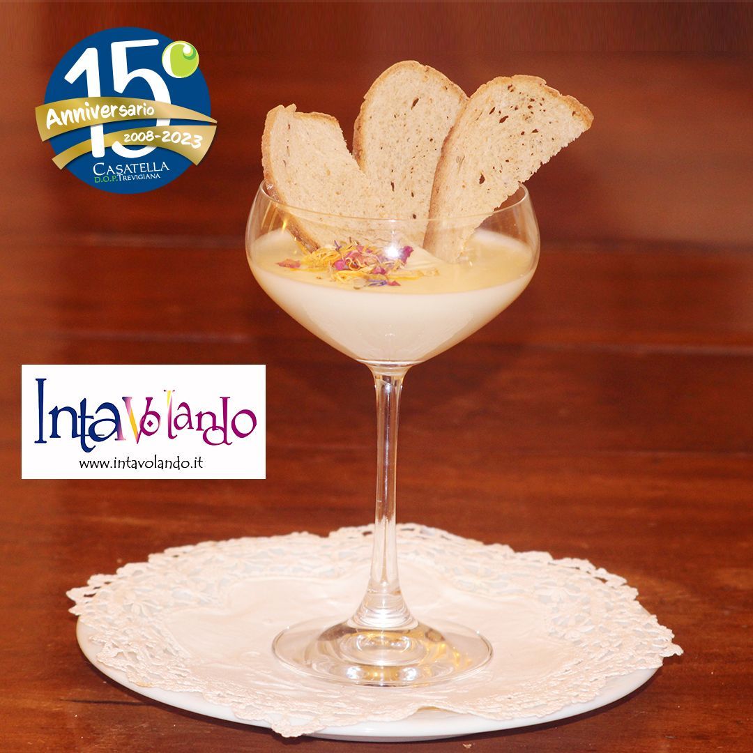 Dessert in un bicchiere da martini su un centrino di pizzo, guarnito con biscotti wafer, su un tavolo di legno.
