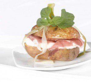 Panino grigliato con salmone e salsa, guarnito con lattuga e servito su un piatto bianco.