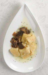 Pasta cremosa con funghi saltati in padella, servita su un piatto bianco a forma di lacrima.