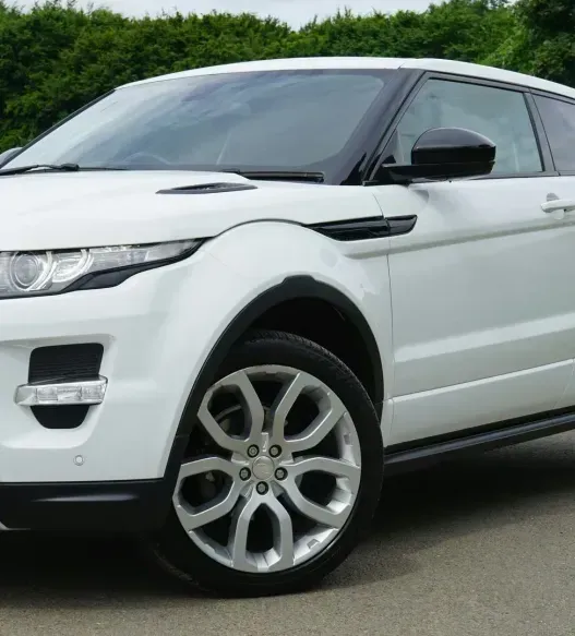 A white range rover is parked on the side of the road