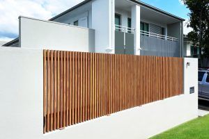 A white house with an aluminium wooden fence in front of it.