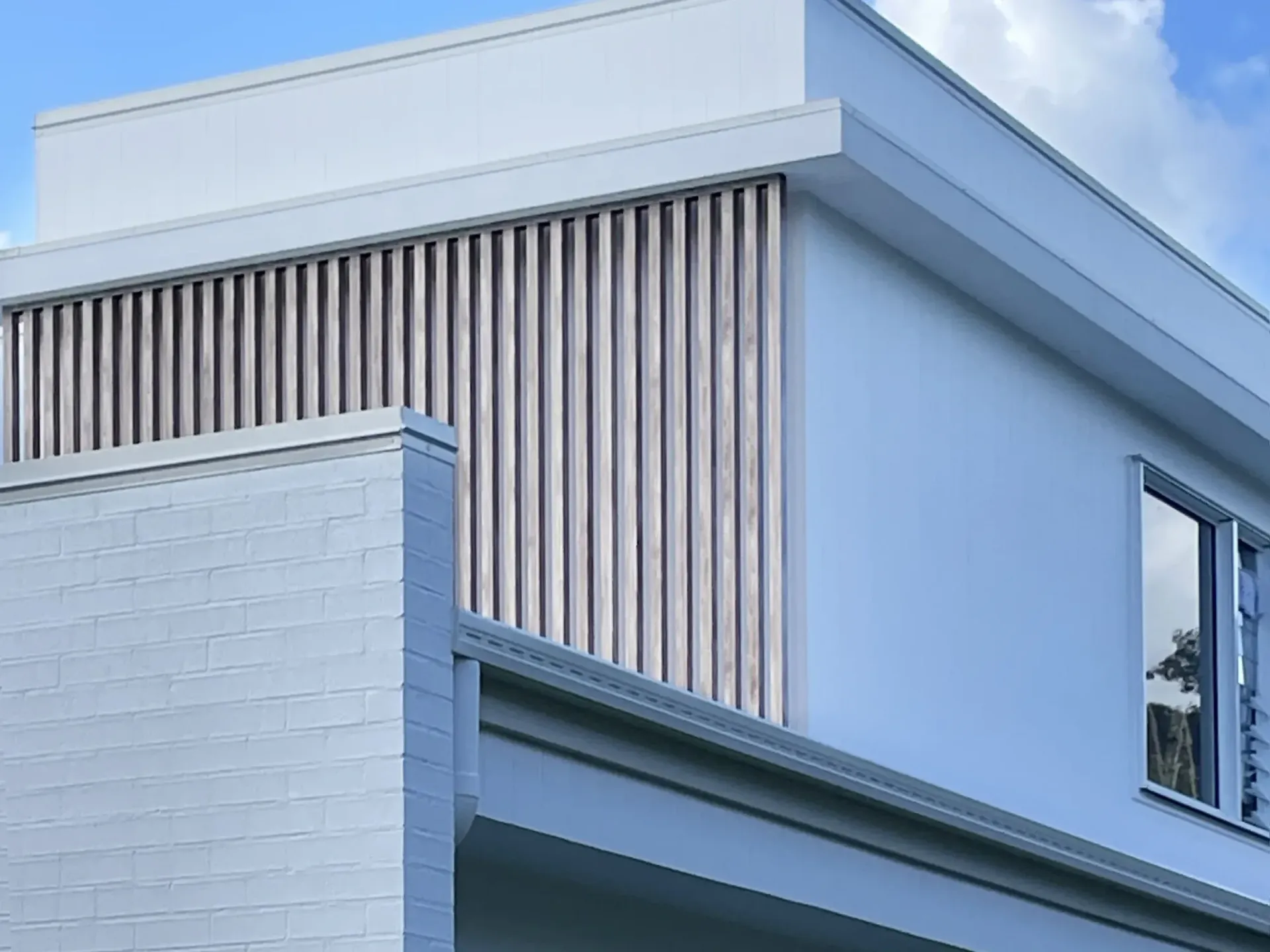 A white house with a balcony and a blue sky in the background.