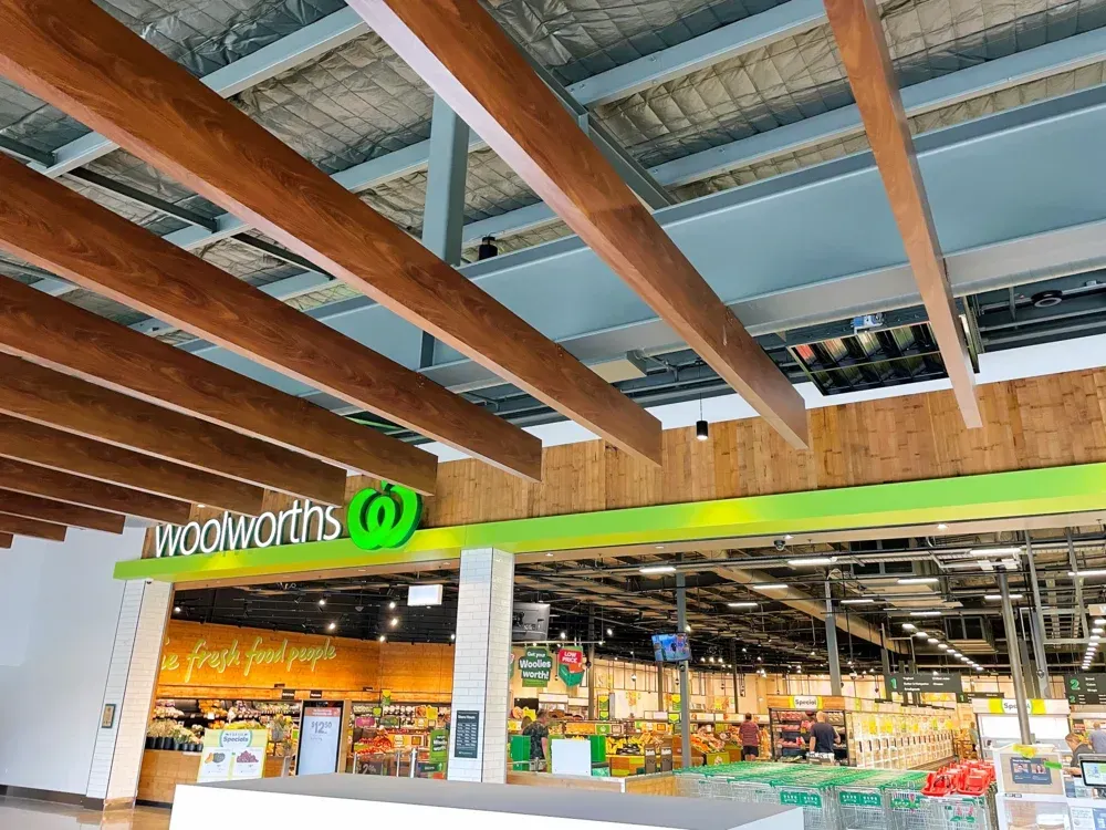 A grocery store with a wooden ceiling and a green sign that says woolworths