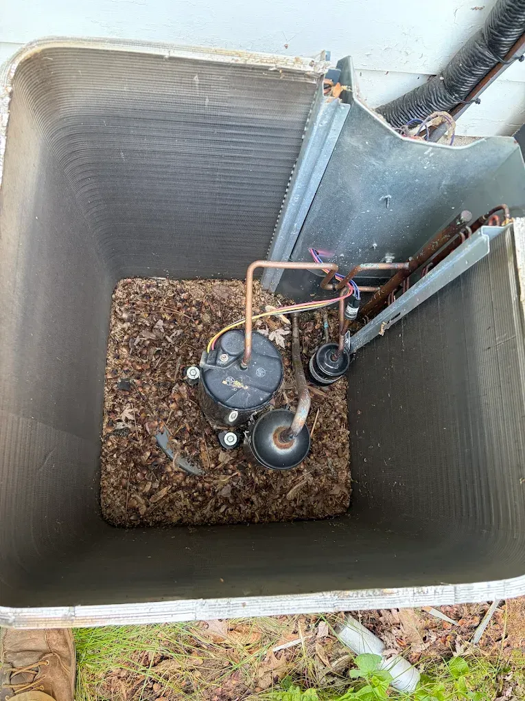 Open HVAC unit with a compressor and copper tubing inside a metal outdoor enclosure.
