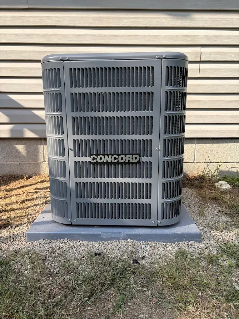 Gray Concord outdoor air conditioner unit beside a house wall on a concrete pad