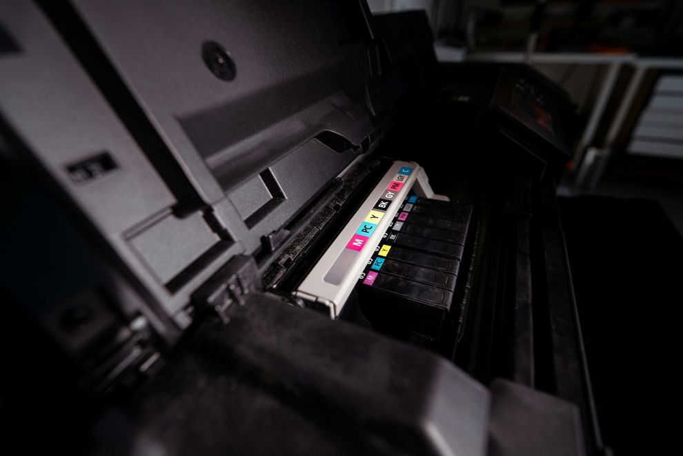 Printer ink cartridge bay with colorful ink labels inside a machine