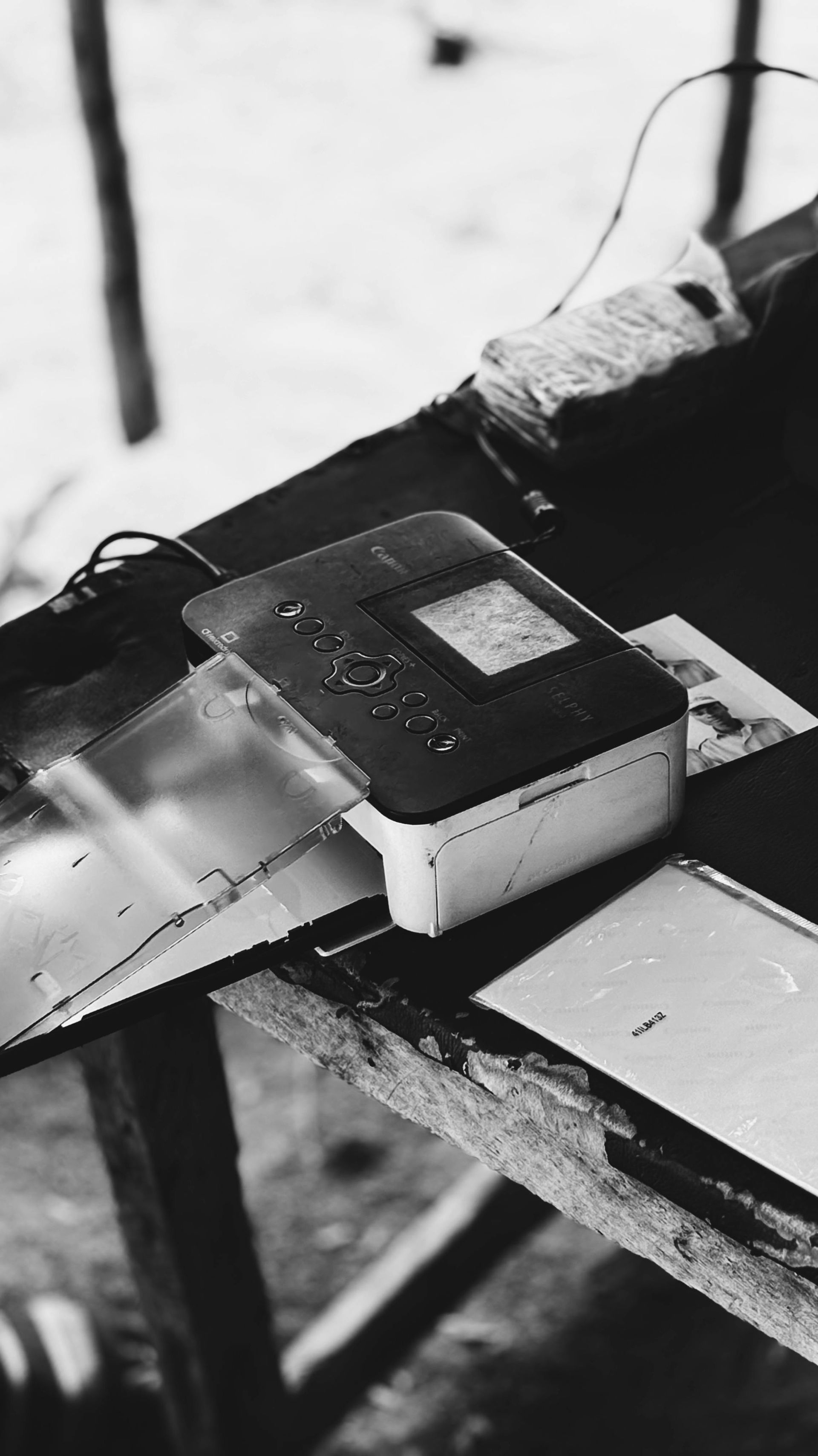 Black-and-white close-up of a small device on a wooden table with cables attached.