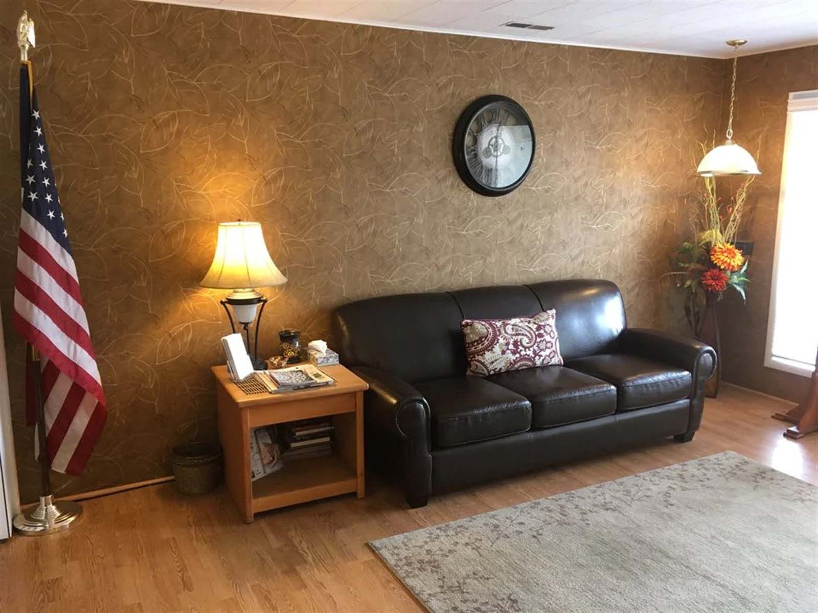 A living room with a couch , lamp , and american flag.