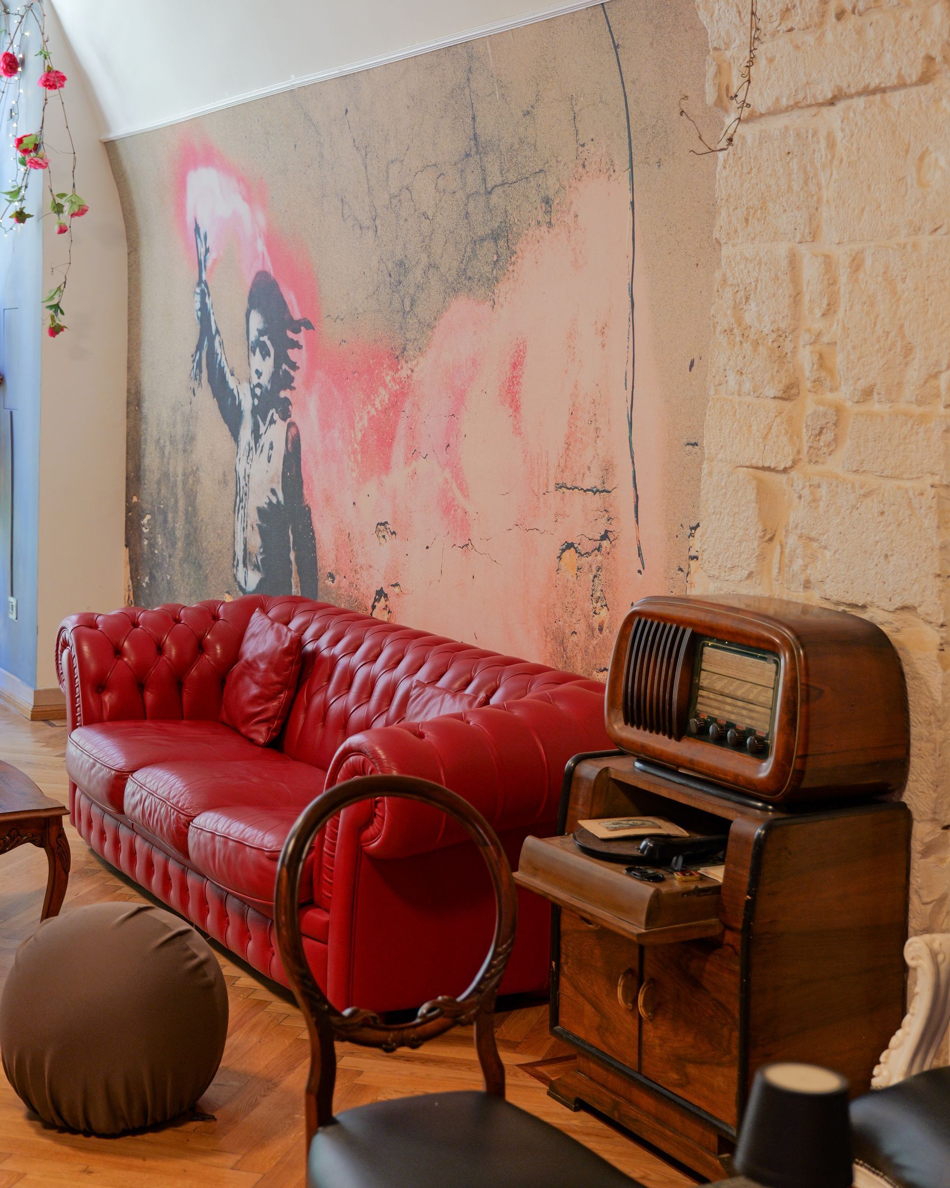 Divano in pelle rossa in una stanza con un murale in stile Banksy e una radio d'epoca.