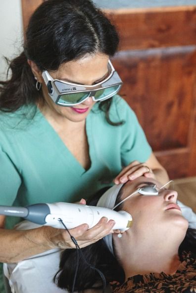 A woman is getting a laser treatment on her face.