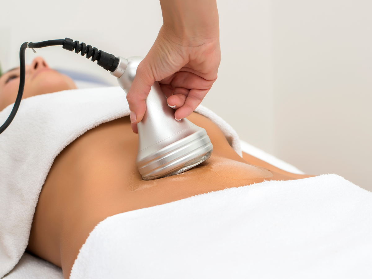 Person receiving abdomen treatment with a handheld device, in a medical setting.
