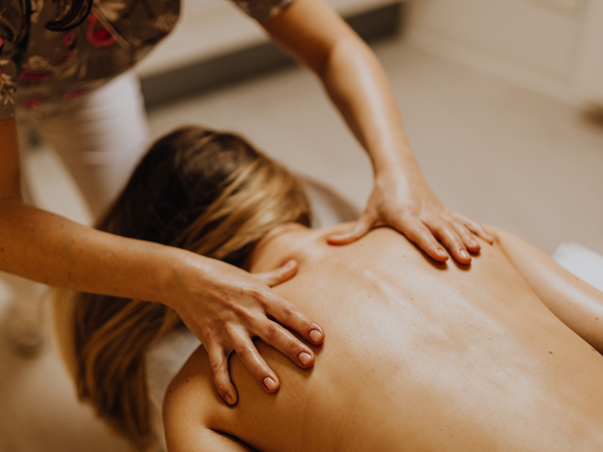 Person receiving back massage in a spa setting, therapist's hands on back.