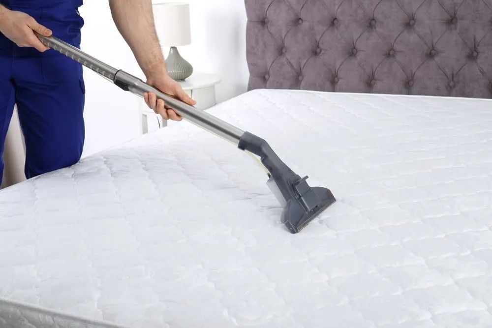 Person Vacuuming a White Mattress in A Bedroom — Clean Coast Carpet Cleaning in Port Stephens, NSW