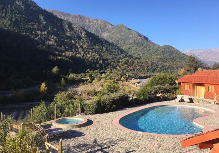 Complejo turístico de montaña con dos piscinas azules junto a un edificio de techo rojo.