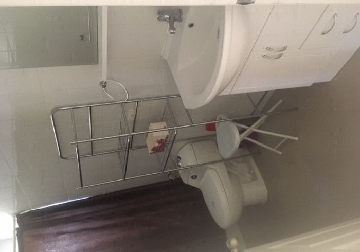 Baño con estante empotrado, toallero y portarrollos de papel higiénico junto al lavabo.
