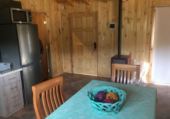Cocina revestida de madera con mesa, sillas, refrigerador y un centro de mesa con cesta.
