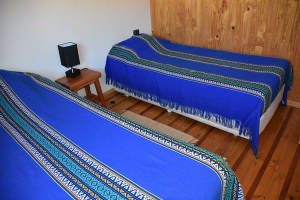 Dos camas con colchas de rayas azules en un sencillo dormitorio de madera.