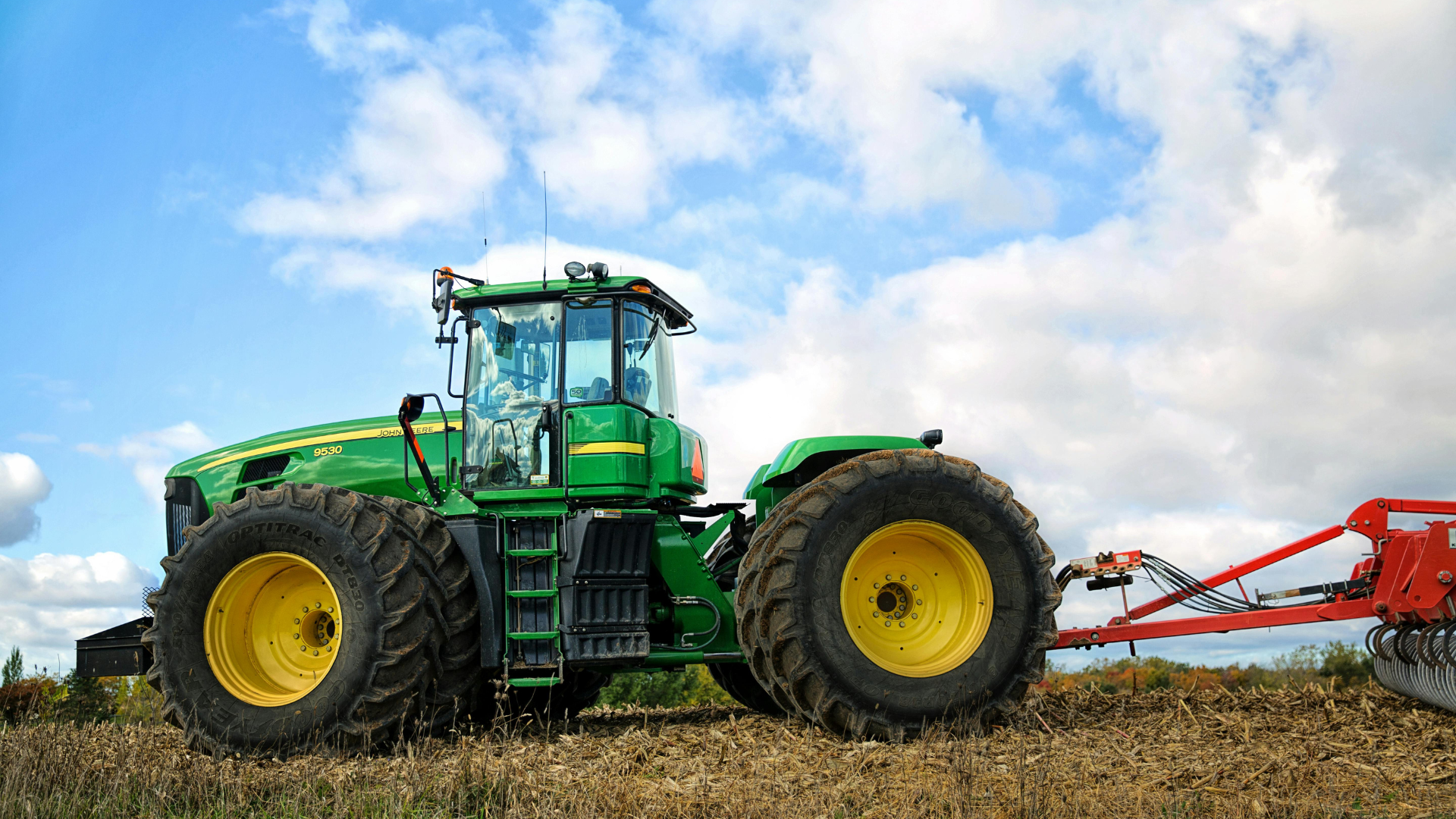 Person working on the engine of a red tractor outdoors