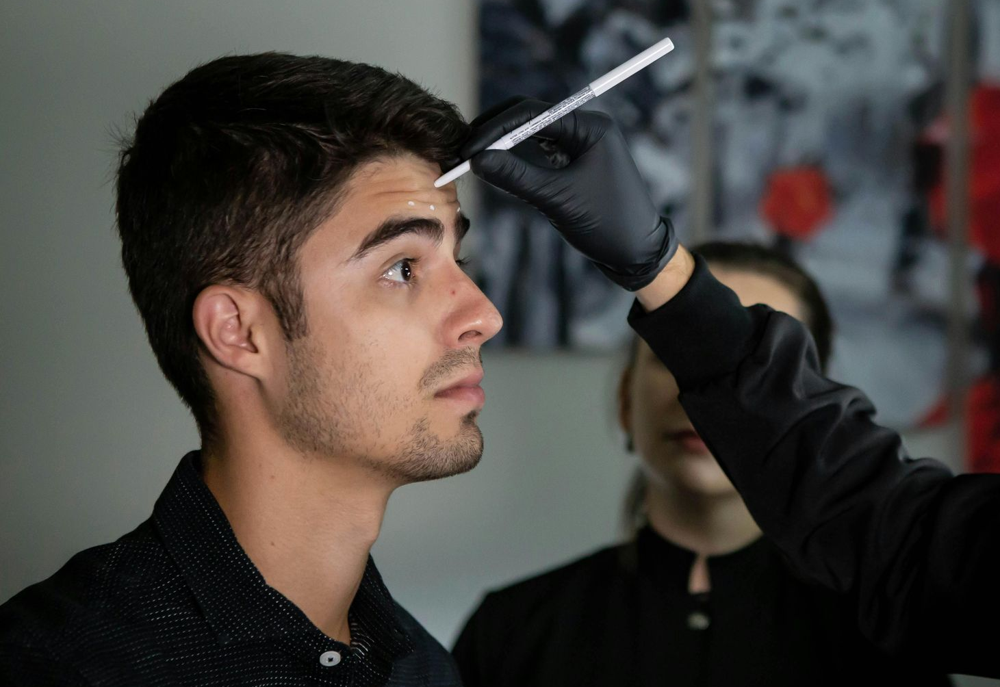  A male patient is getting marked by Kyle Farr for injection points for Botox.