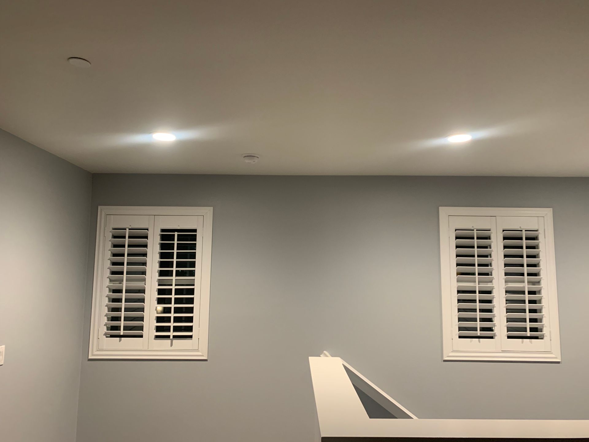 A room with two windows and shutters on the walls