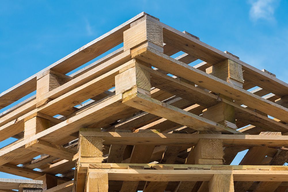 A stack of wooden pallets against a blue sky.