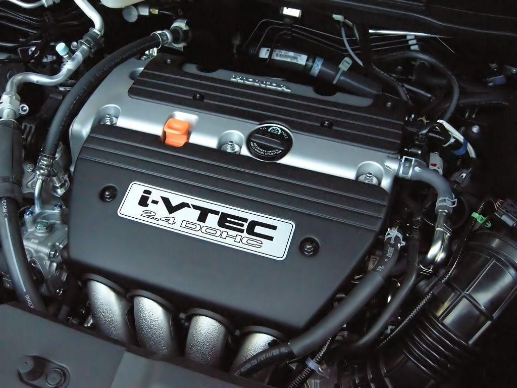 Honda i-VTEC engine. Black engine cover with white i-VTEC logo, orange cap, and various hoses.