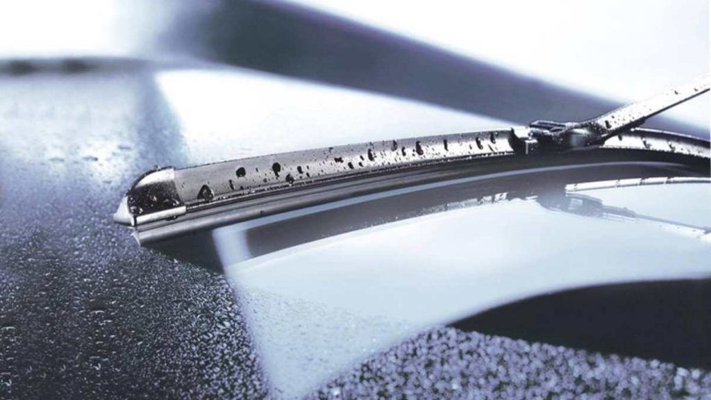 Windshield wiper wiping a wet car surface.