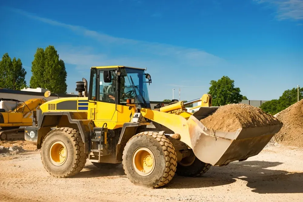 Yellow construction loader with a full bucket of sand, under a blue sky. — Shantui QLD in Warwick, QLD