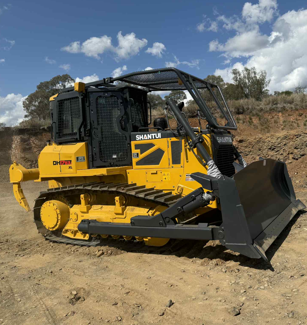 Yellow Shantui Bulldozer on A Dirt Surface Under a Partly Cloudy Sky — Shantui QLD in Kingsthorpe, QLD