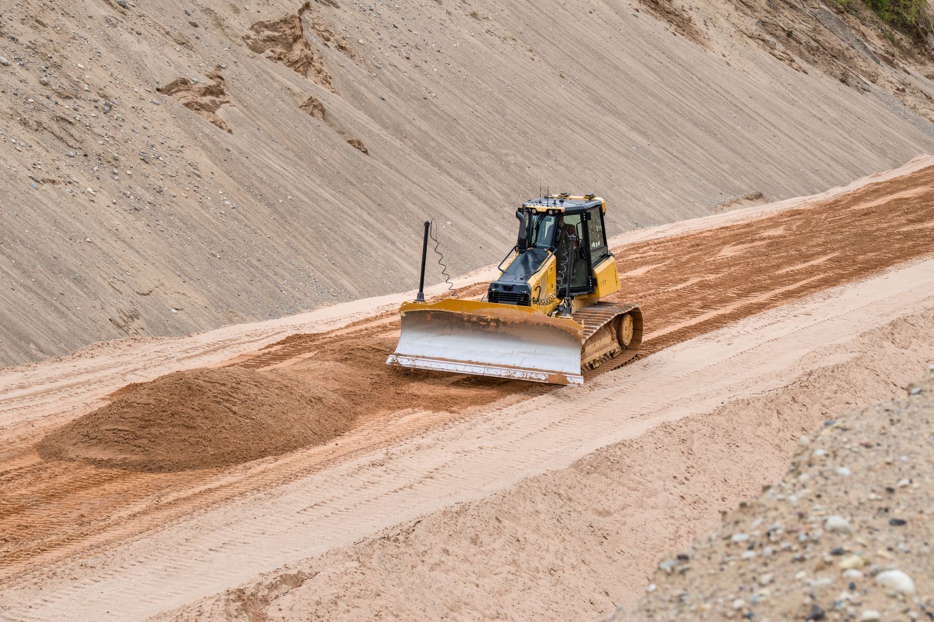 A bulldozer, yellow, grading soil on a construction site