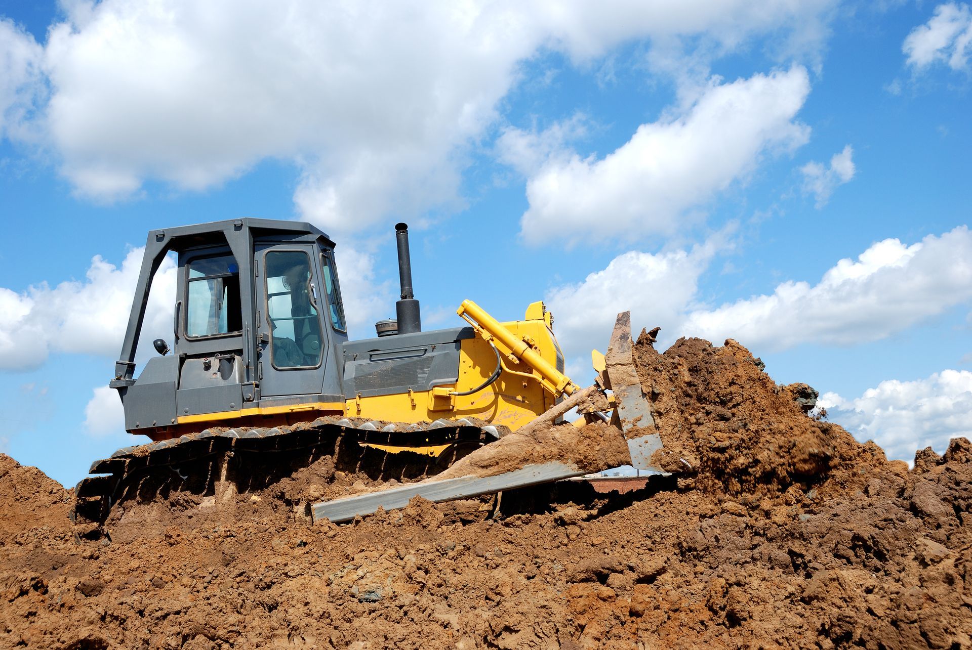 A bulldozer, yellow, grading soil on a construction site