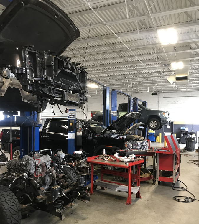 Auto repair shop with cars on lifts and a red workbench in a garage interior