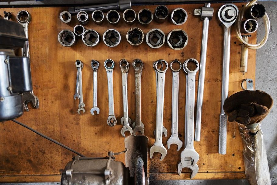 Tools organized on a wooden workshop wall: sockets, wrenches, and a tire iron.