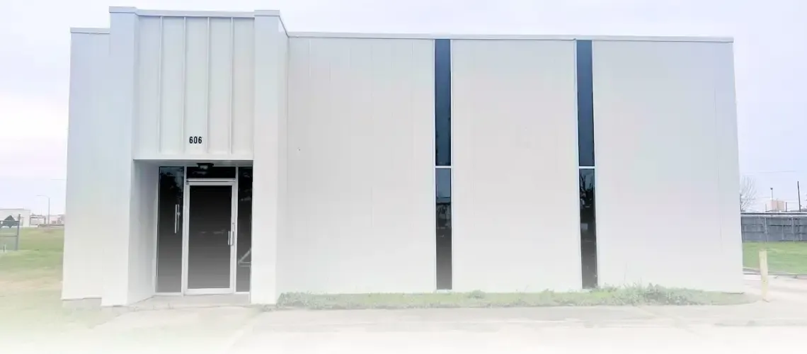 A white, single-story commercial building with a recessed entrance and three tall, narrow windows. A sign above the door reads 