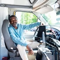 Man in a blue shirt driving a vehicle.