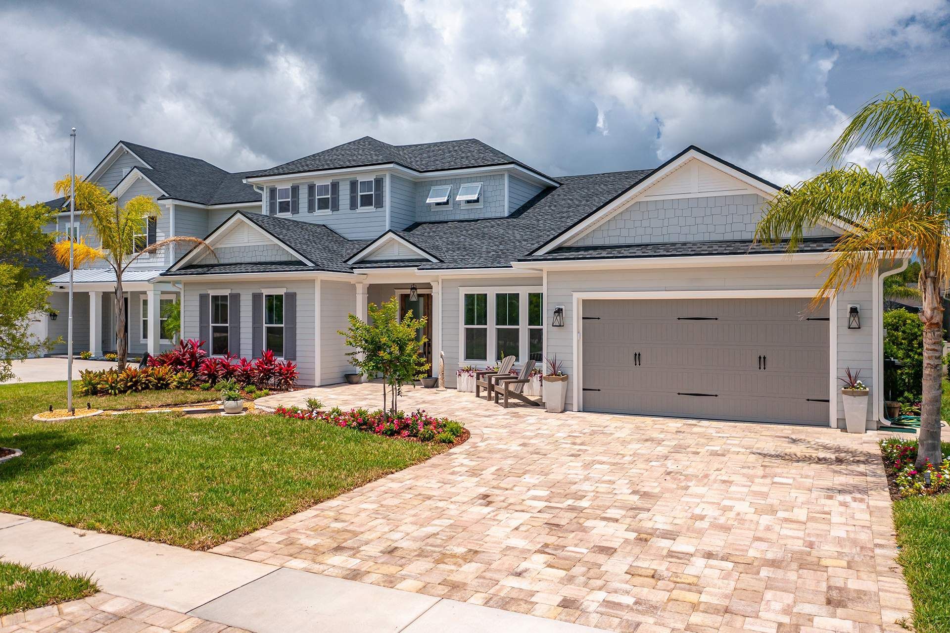 A large white house with a brick driveway and a garage.