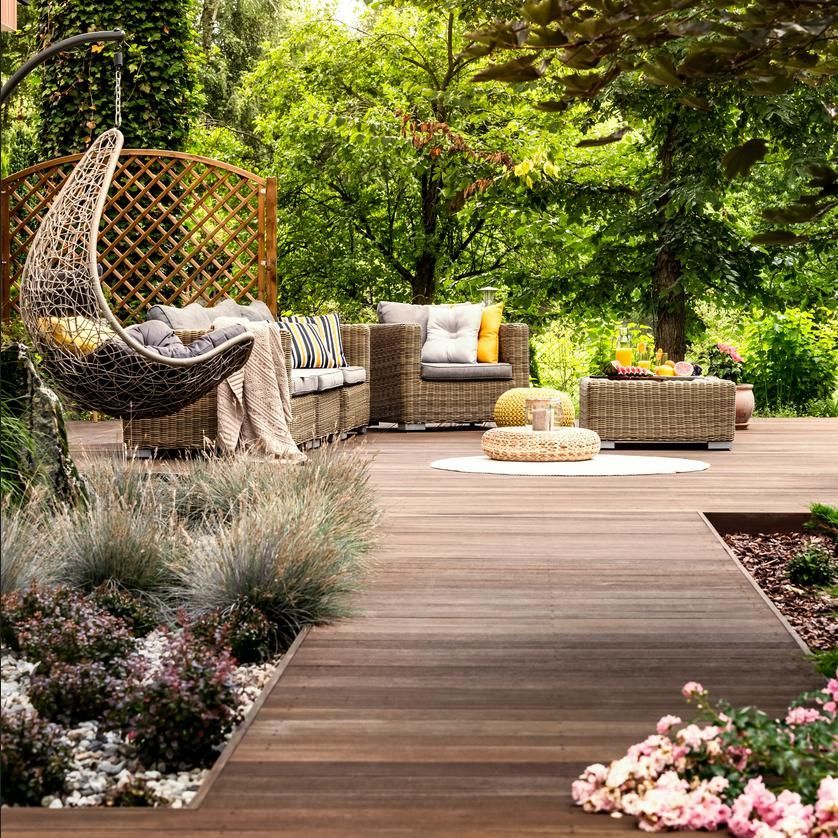 A wooden deck with wicker furniture and a hanging chair.