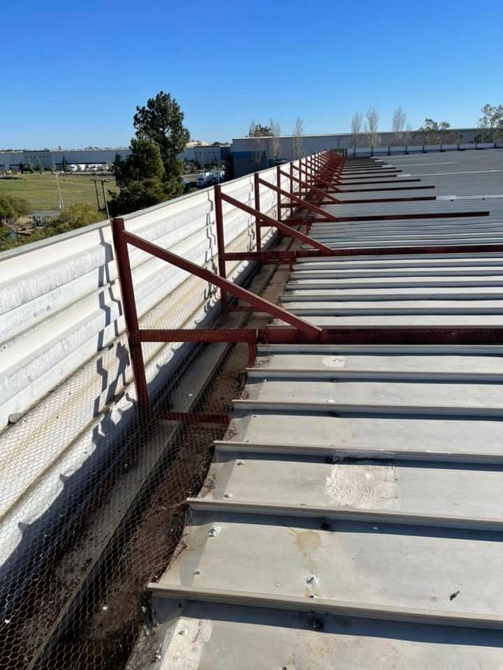 Rooftop walkway with red metal guardrails and white panels along a building edge