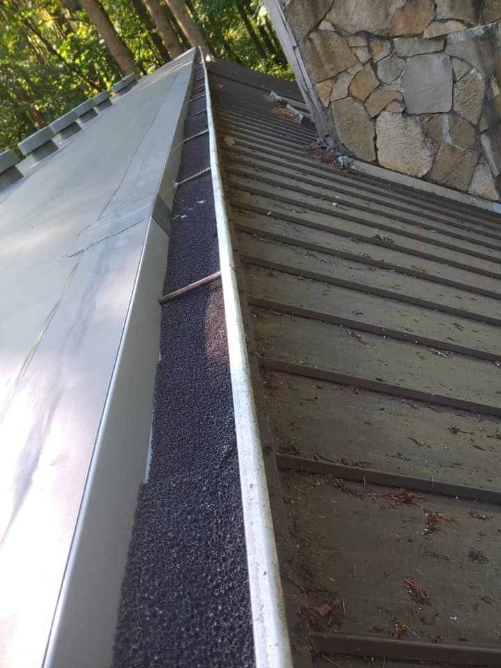 Roof gutter and sloped metal roof beside a stone wall, viewed from above