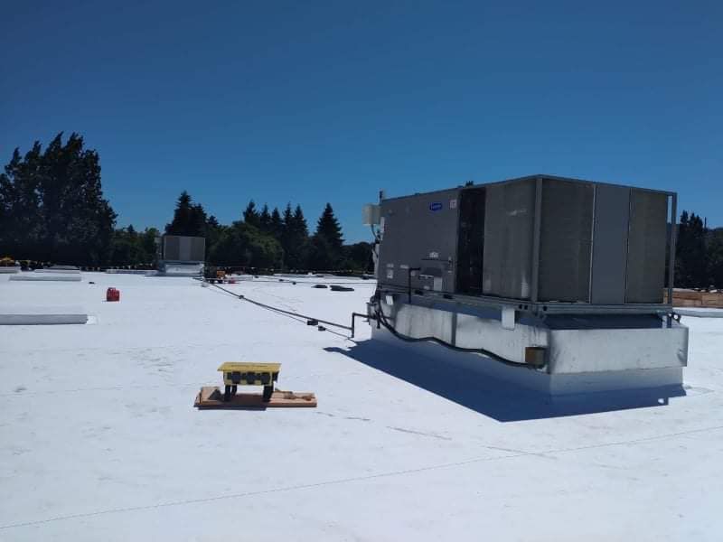 Rooftop HVAC unit on a commercial flat roof under a clear blue sky
