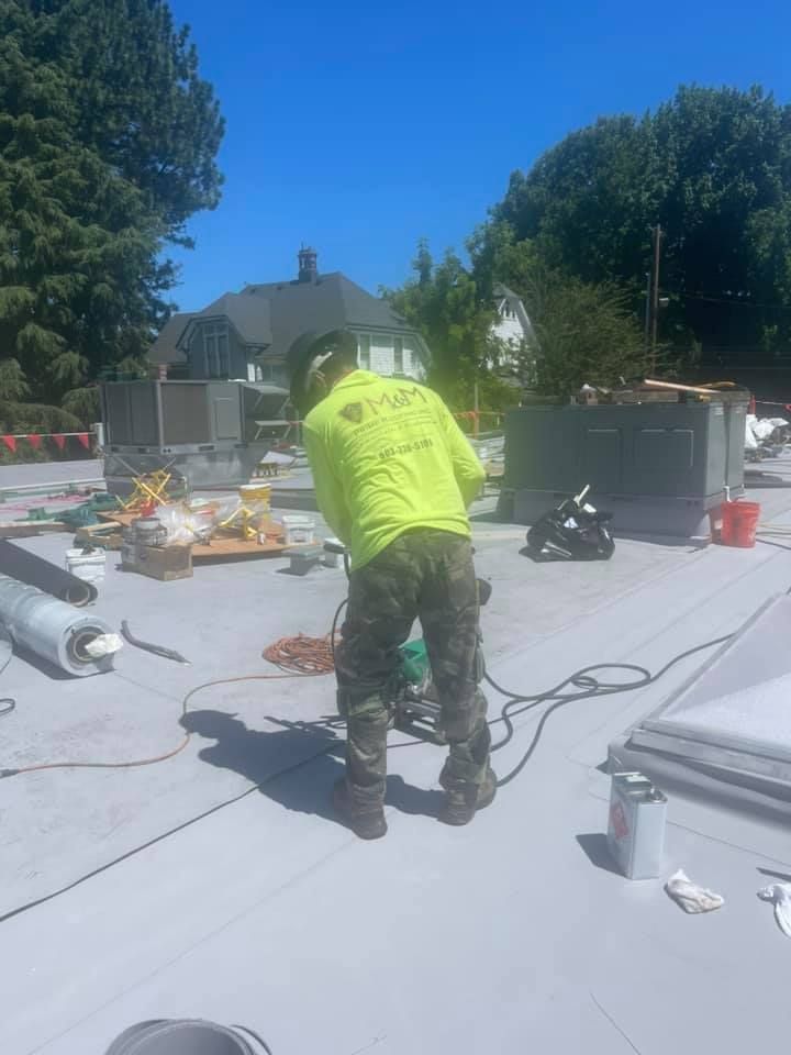 Worker in neon shirt operating tools on a rooftop under construction on a sunny day