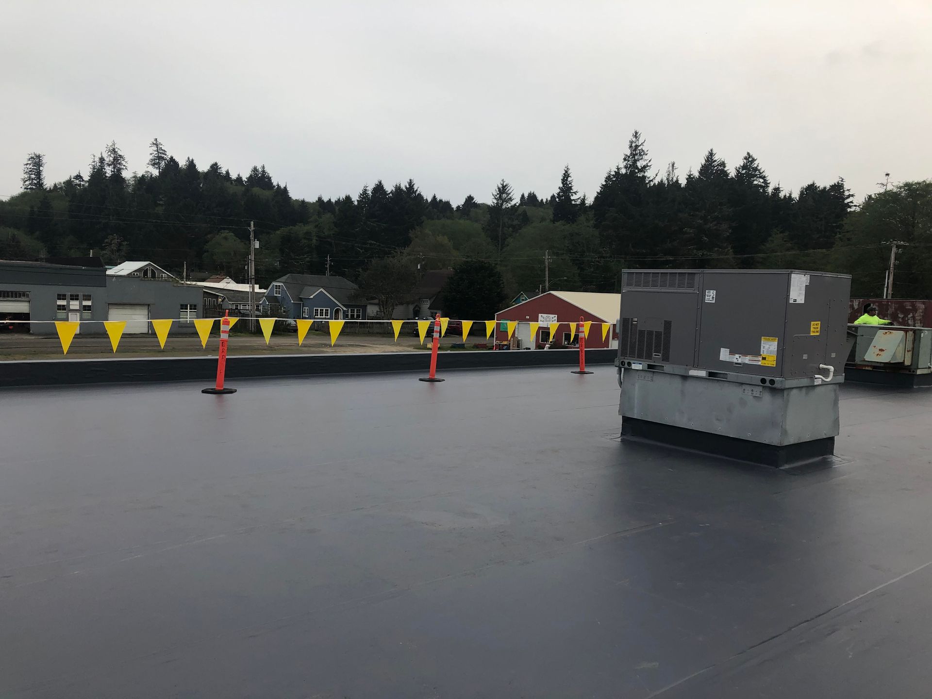Large paved lot with yellow barriers, orange cones, and gray equipment under an overcast sky