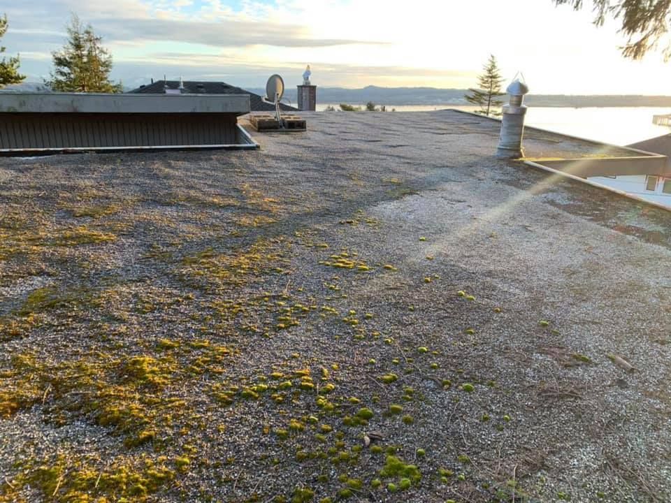 Rooftop gravel surface at sunrise with vents and distant water view
