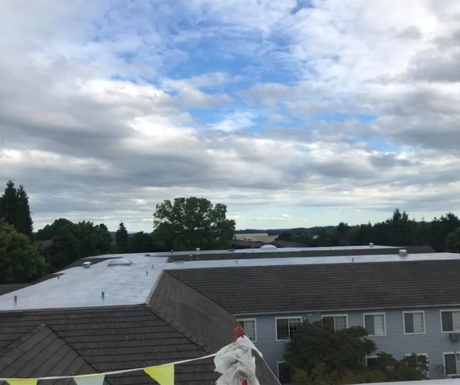 Cloudy sky over apartment rooftops with trees in the distance