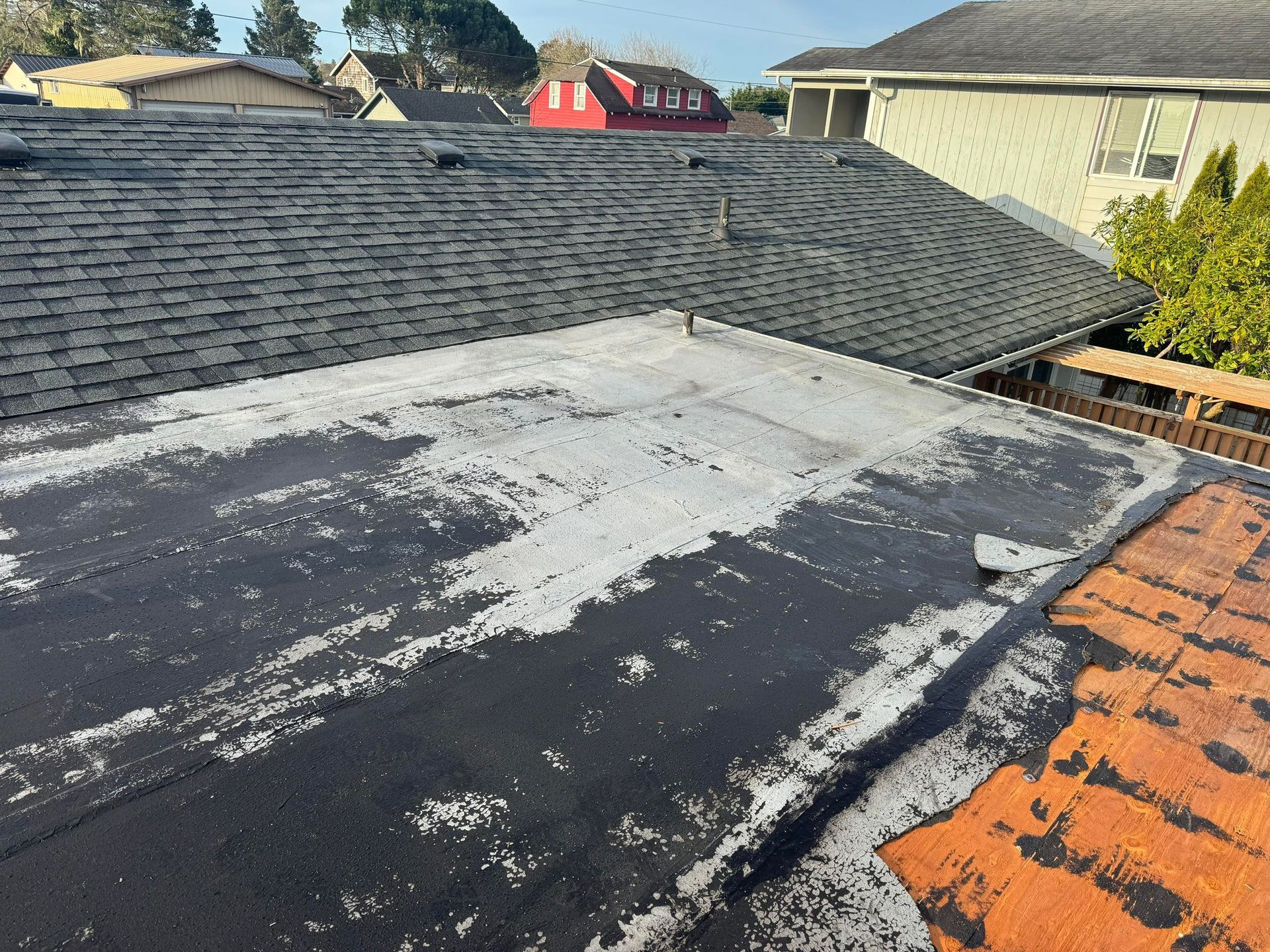 Flat rooftop with dark gray shingles, a weathered white section, and orange tiles at the edge.