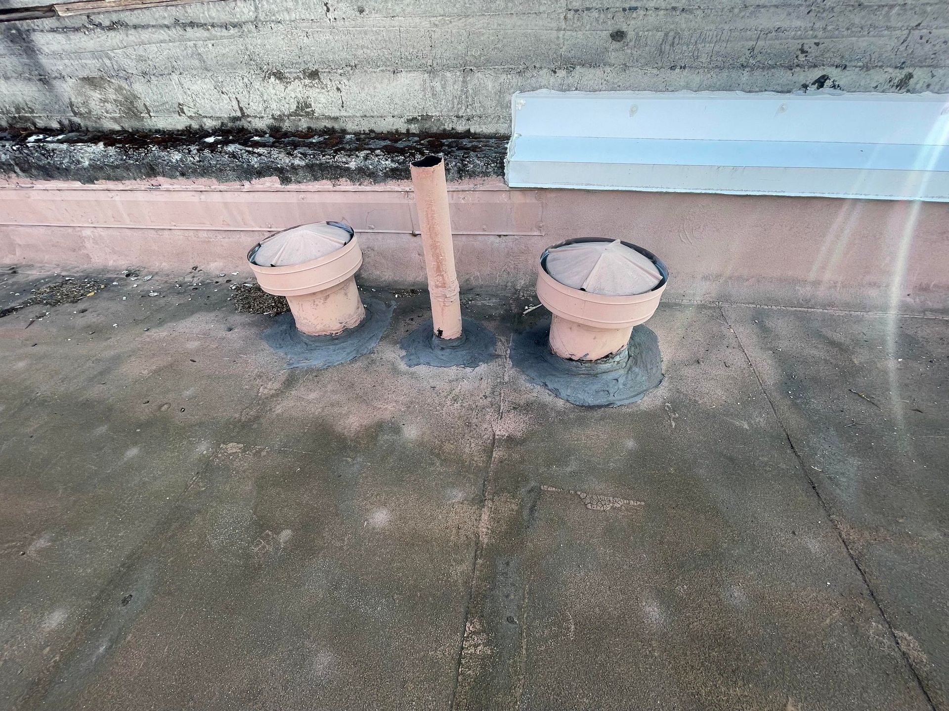 Two empty beige flower pots on a concrete terrace beside a wall and metal post