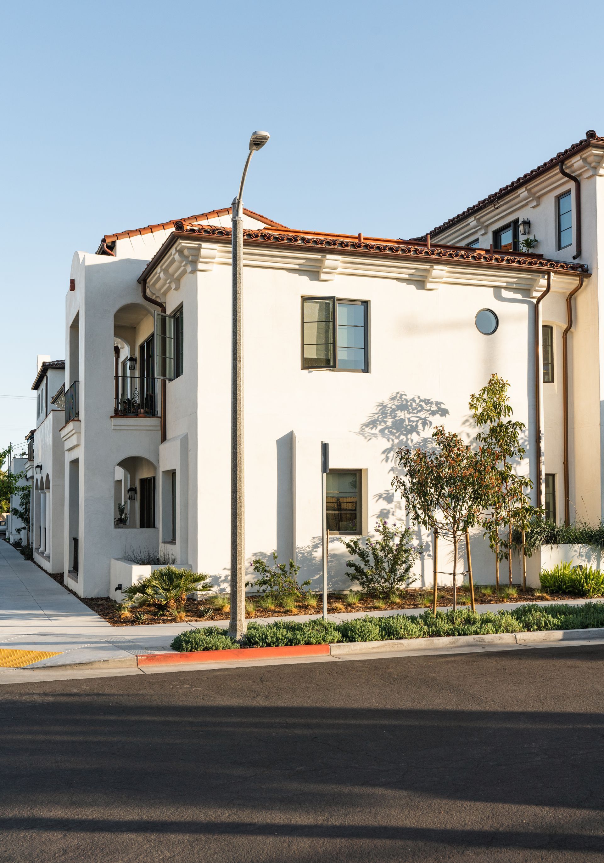 A white building with a red tile roof is next to a street