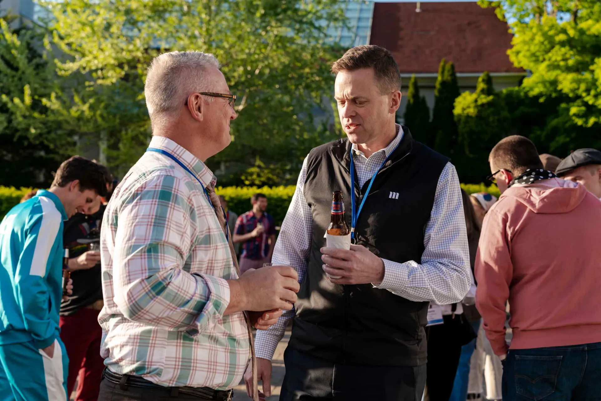 Two men are standing next to each other talking in a park.